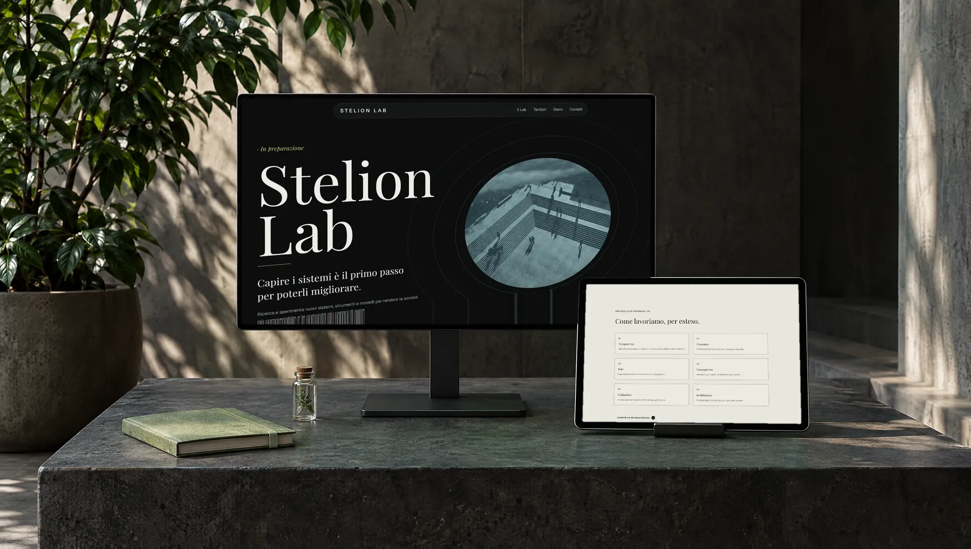 Il sito di Stelion Lab su monitor e tablet, su un blocco di cemento scuro